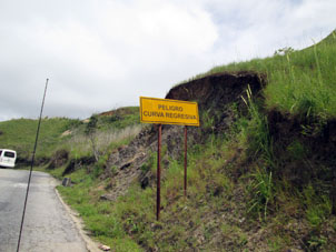 Вдоль дороги плакаты об опасном горном серпантине (извивы в обе стороны).