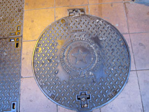 Крышка колодца электропроводки, на ней написано "Сиятельный Муниципалитет Гуаякиля".