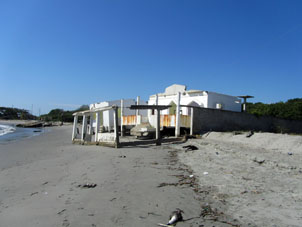 Смываемые волной развалины домика на берегу.