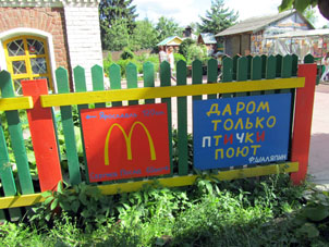 Pancartas chistosas sobre la valla: "Gratuitamene solo los pájaros cantan" y con espicificación de distancia hasta McDonald's próximo.