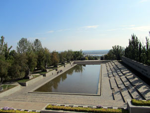 Vista a estanque rectanhular y estatuas con fragmentos de la Batalla cerca del mismo. Lejos se puede ver el río Volga.